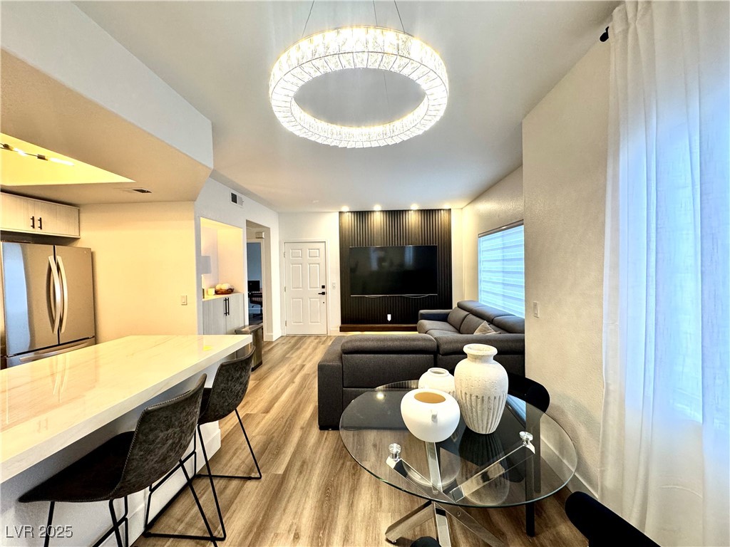 Furnished open-plan living room and kitchen with a gray sectional, TV wall, and marble-look island.