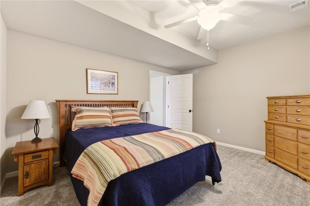 Furnished bedroom with a wooden bed, navy and striped bedding, matching dresser, and ceiling fan.