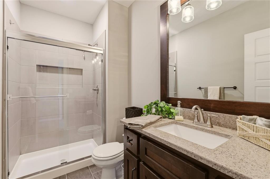 Bathroom with glass-enclosed tiled shower and dark wood vanity with a large mirror.