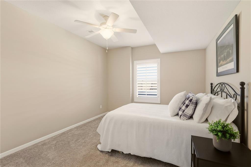 Bedroom with a white bed, black metal headboard, carpet, and shuttered window.