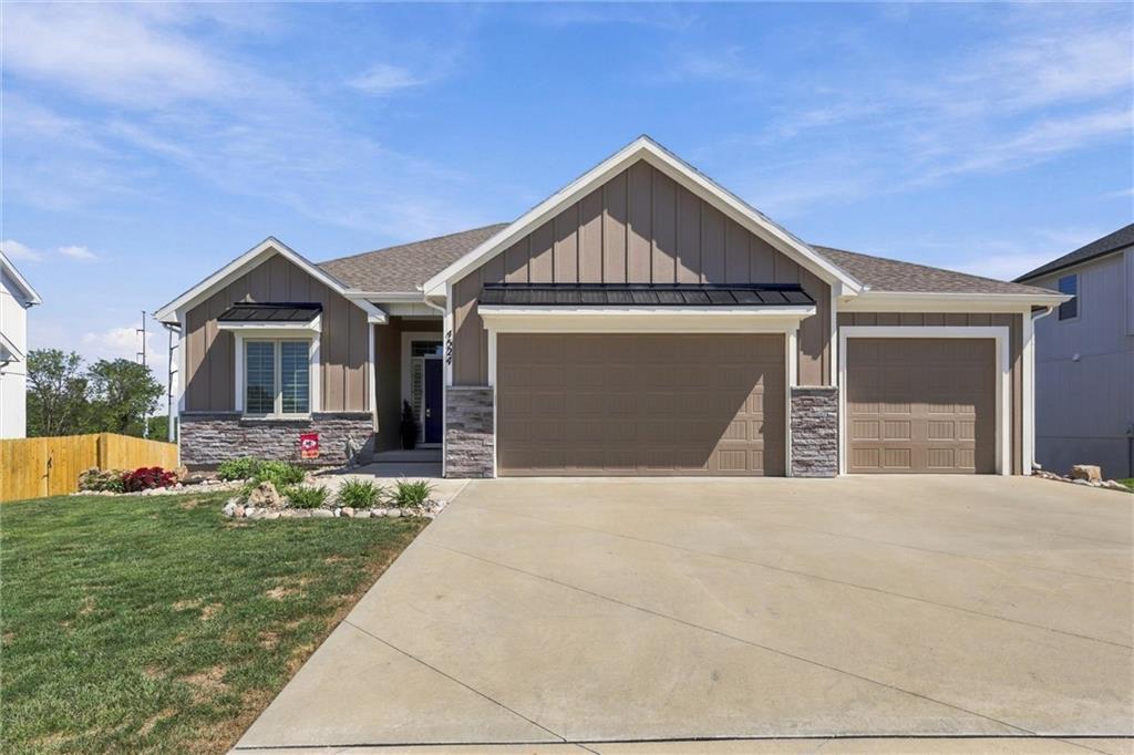 Home exterior with two garage doors, stone accents, and a wide concrete driveway.