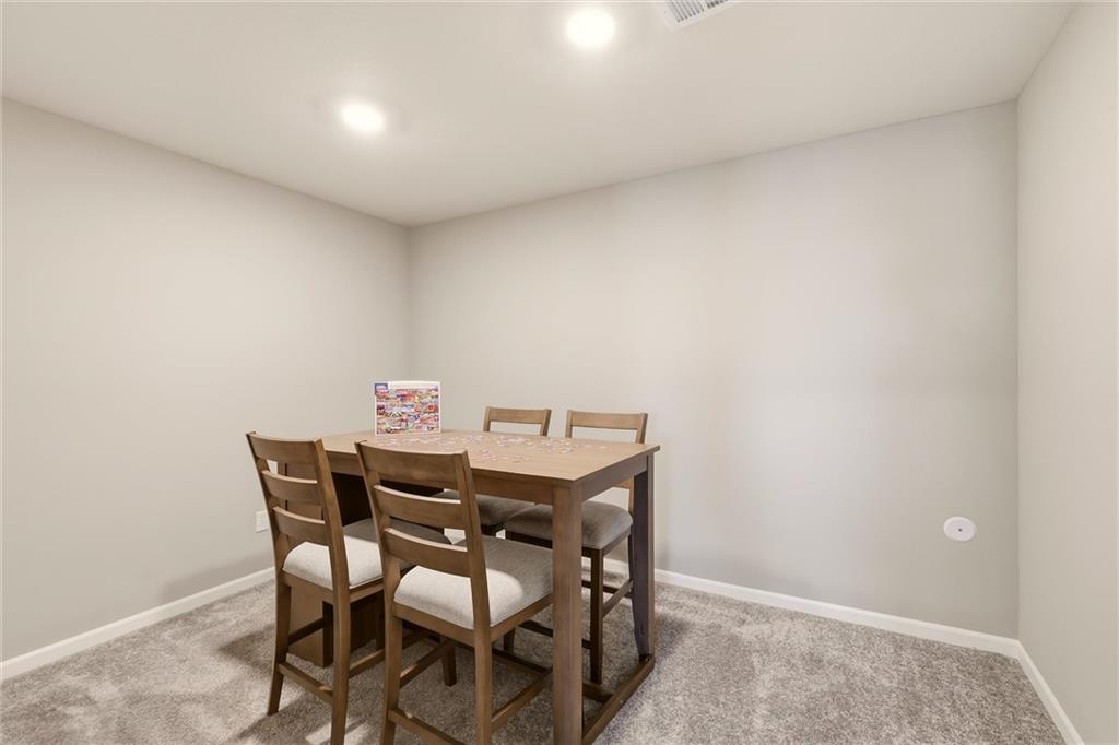 Dining area with a wooden table and four chairs on gray carpet.