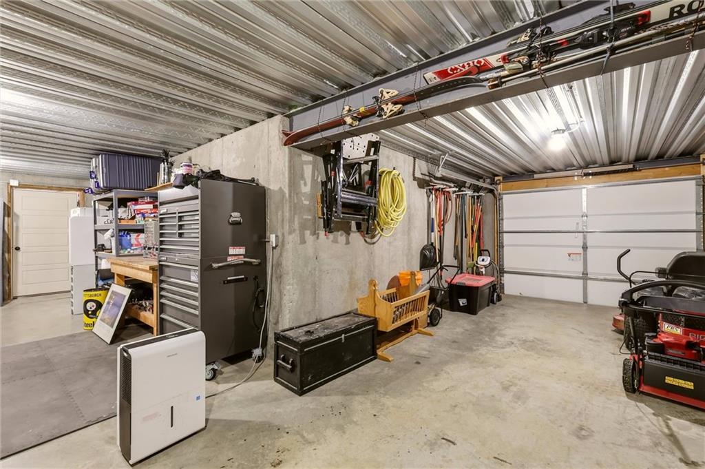 Garage workshop with a large tool chest, workbench, and overhead storage.