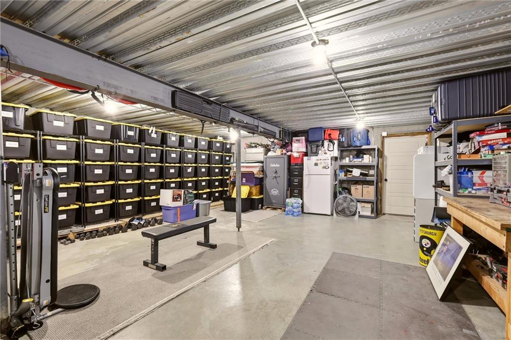 Garage workshop with organized storage bins, a workbench, refrigerator, and exercise equipment.