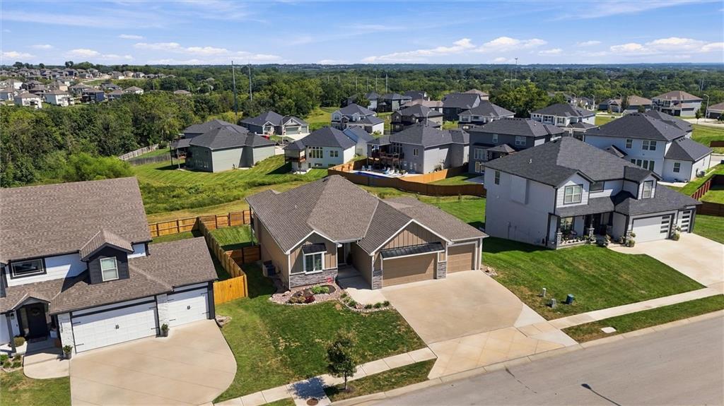 Aerial view of a tan single-story home and neighboring houses in a green suburban development.