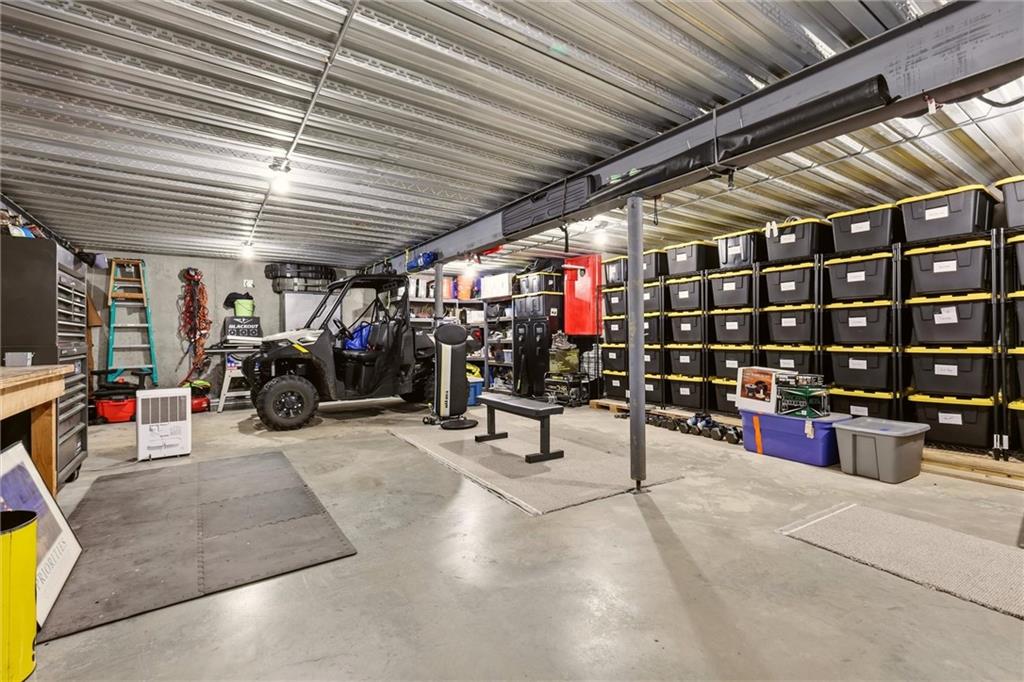 Spacious garage with a utility vehicle, exercise equipment, and rows of storage bins.