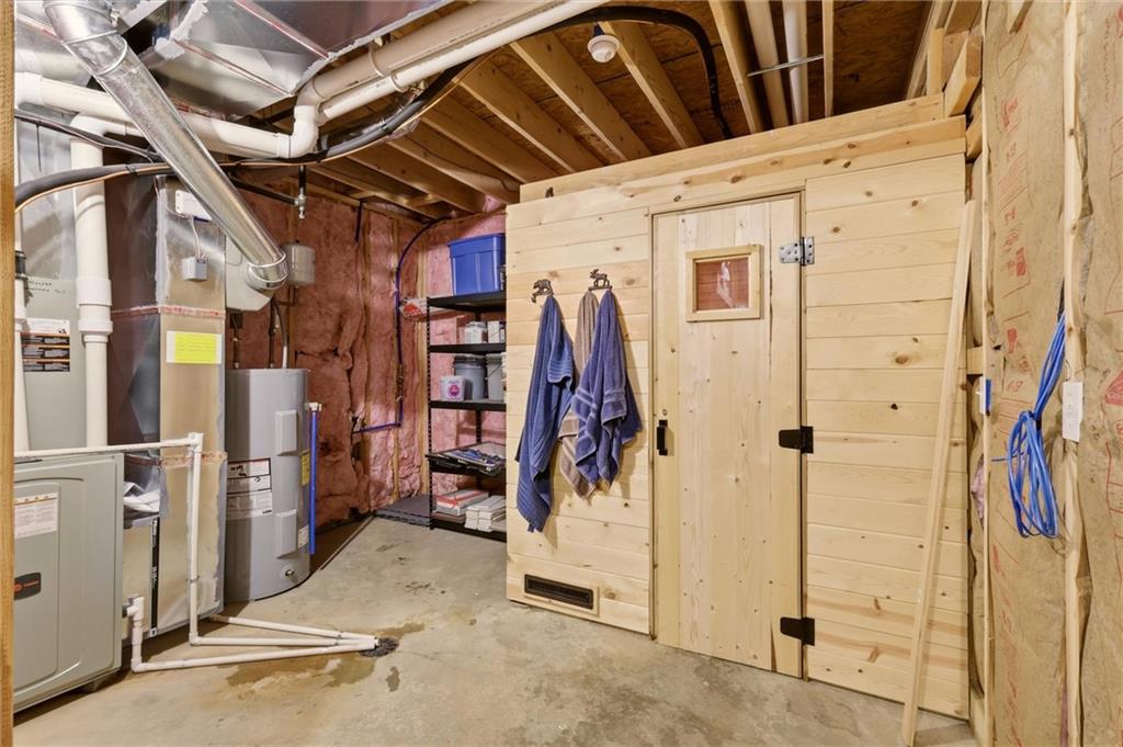 Basement utility area with a wooden sauna beside HVAC equipment and storage shelving.