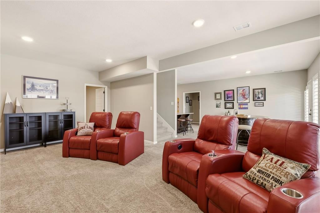 Furnished living room with red leather recliners, beige carpet, and an adjoining dining area.