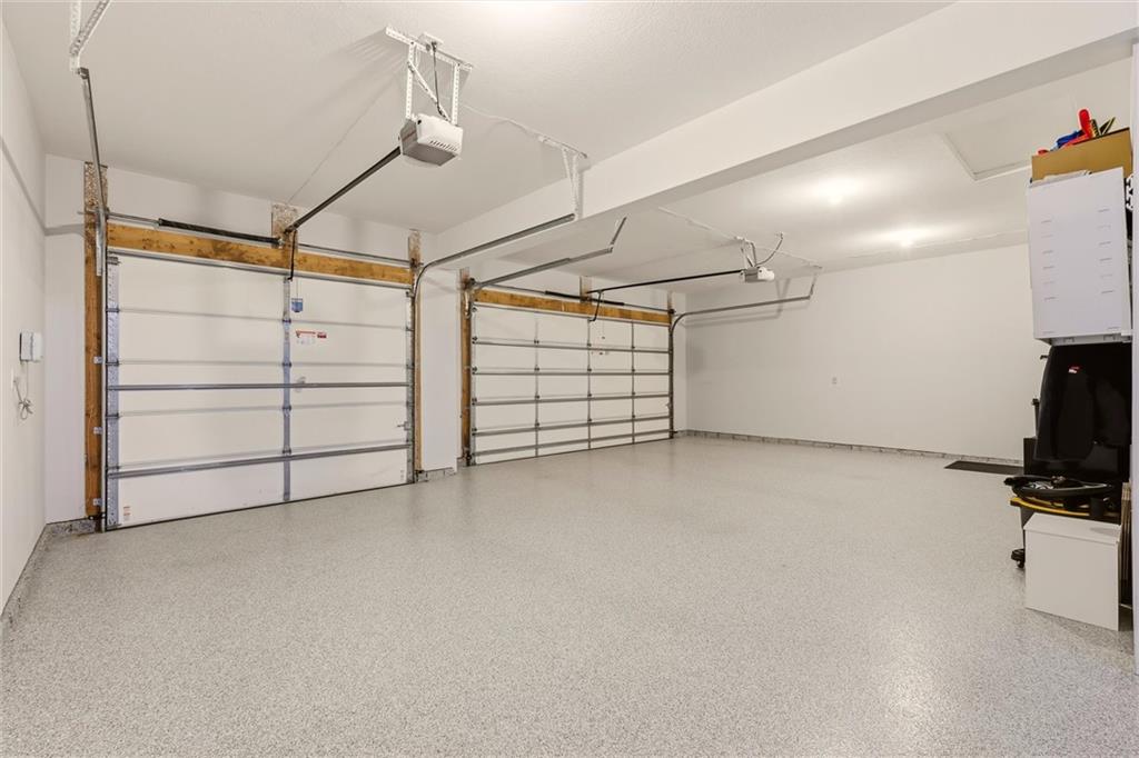 Two-car garage with two overhead doors and a light speckled epoxy floor.