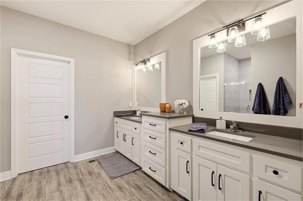 Bathroom with a long double vanity, white cabinets, dark countertops, and large mirrors.