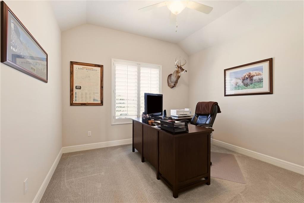Home office with a dark wood desk, shuttered window, and mounted deer head.