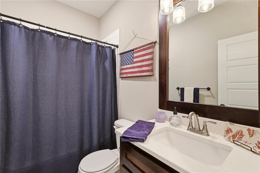 Bathroom with a dark blue shower curtain, white sink, and purple towels on a wood vanity.
