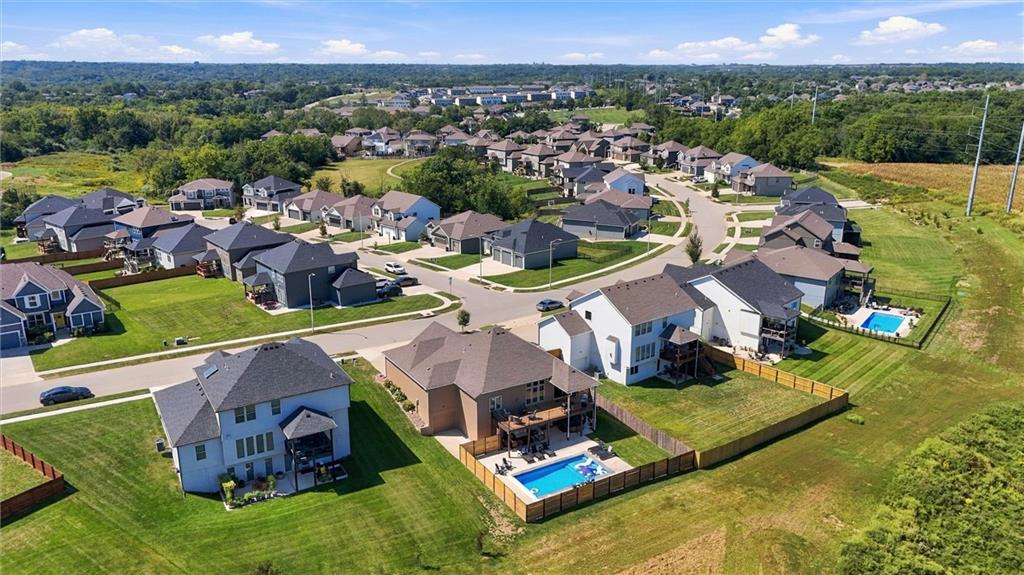 Aerial view of a suburban neighborhood with curving streets and homes with fenced backyard pools.
