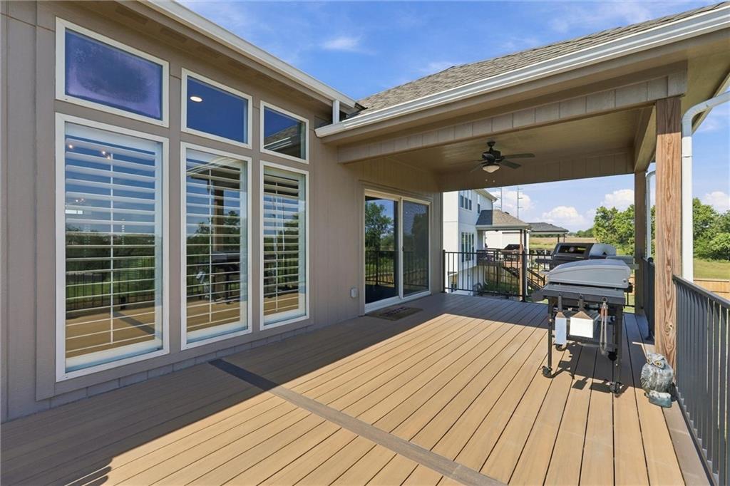 Covered rear deck with two grills, a ceiling fan, and large windows along the house.