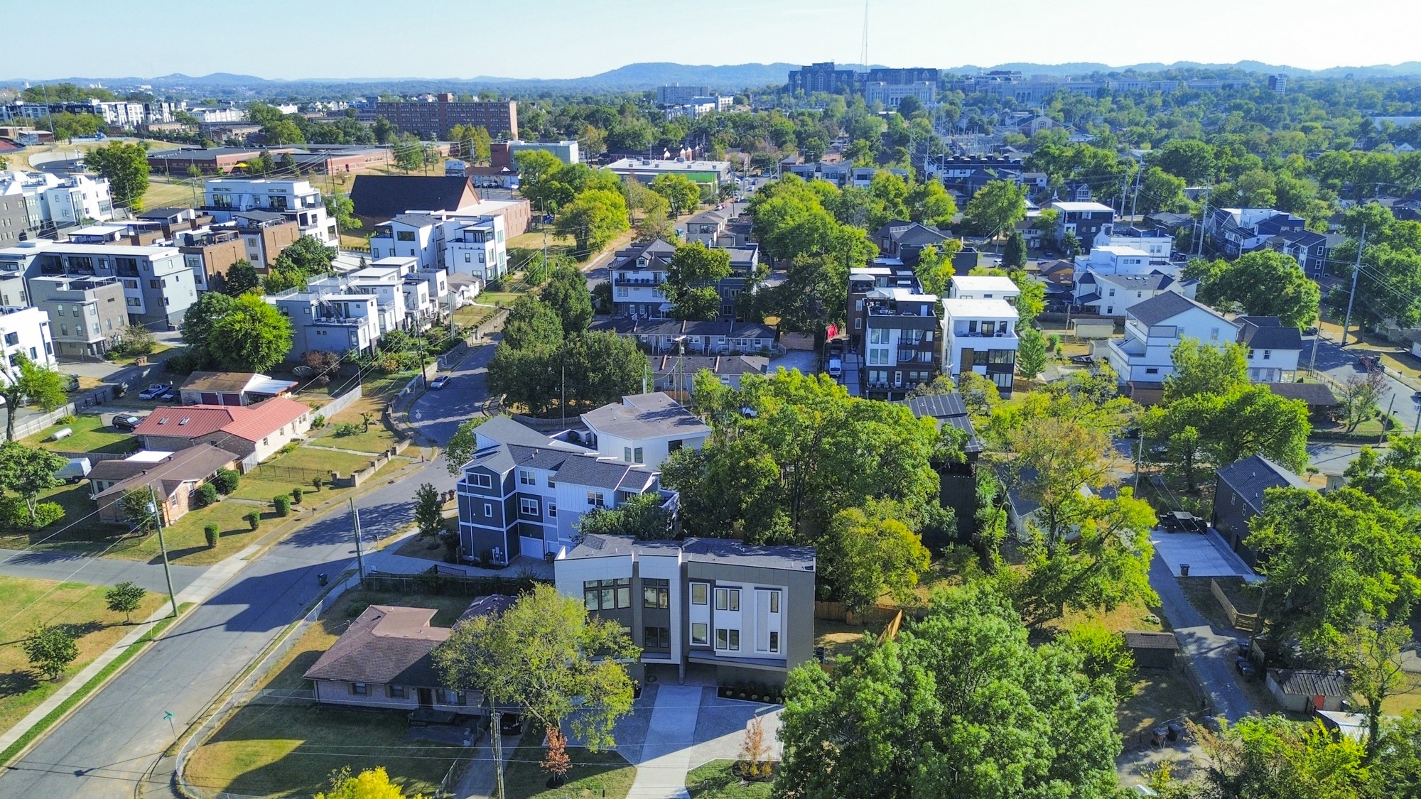 Aerial view of a modern Nashville home amid leafy streets and a mix of newer and older houses.