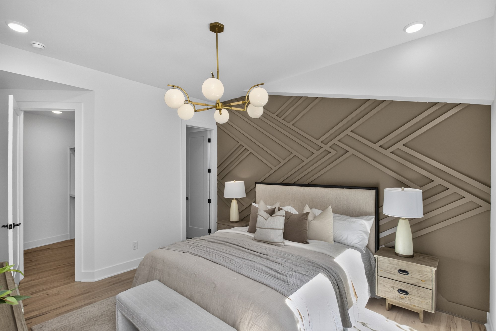 Staged bedroom with a king bed and taupe geometric feature wall