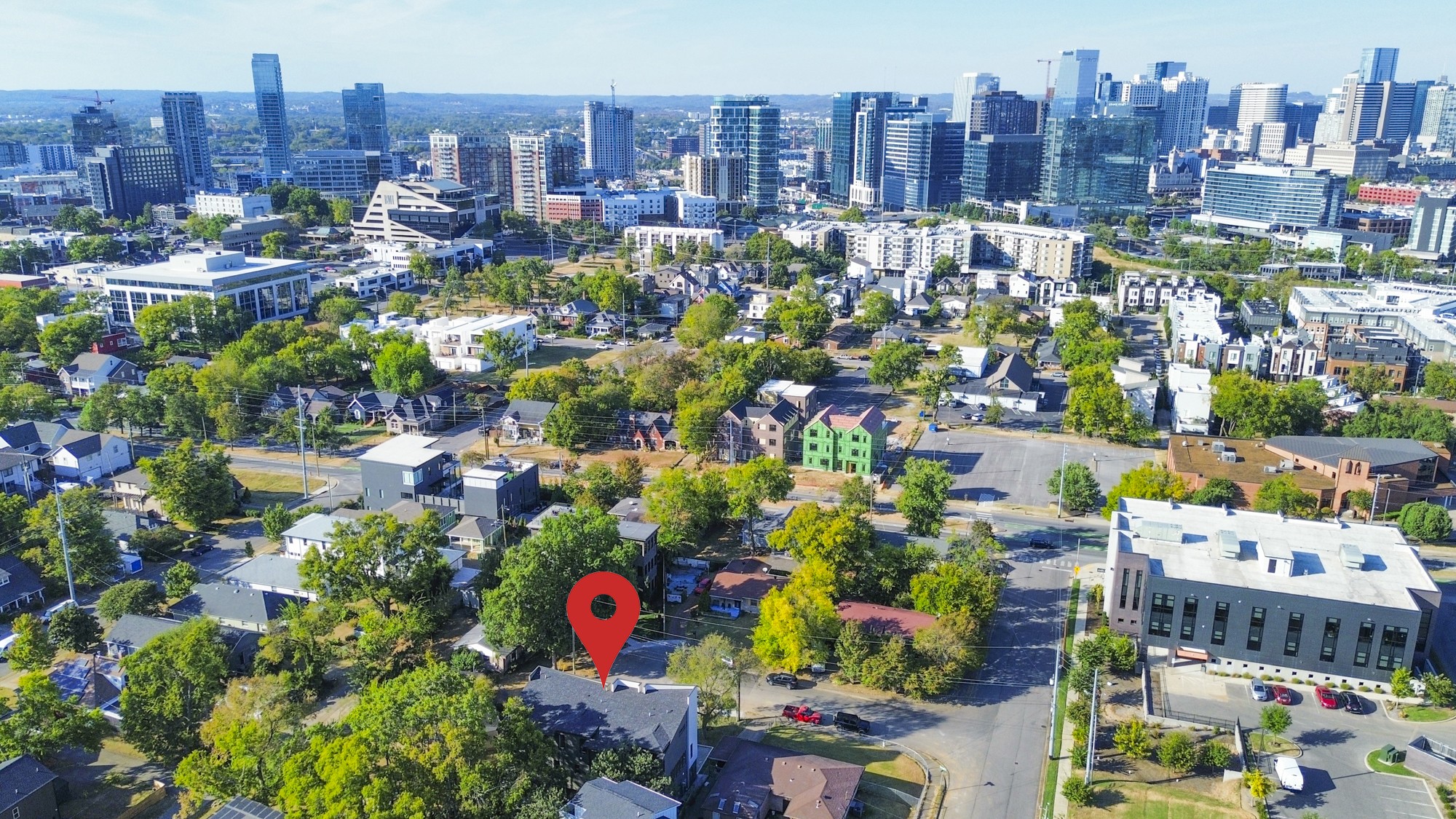 Aerial view of a Nashville neighborhood with a red marker and downtown skyline beyond.