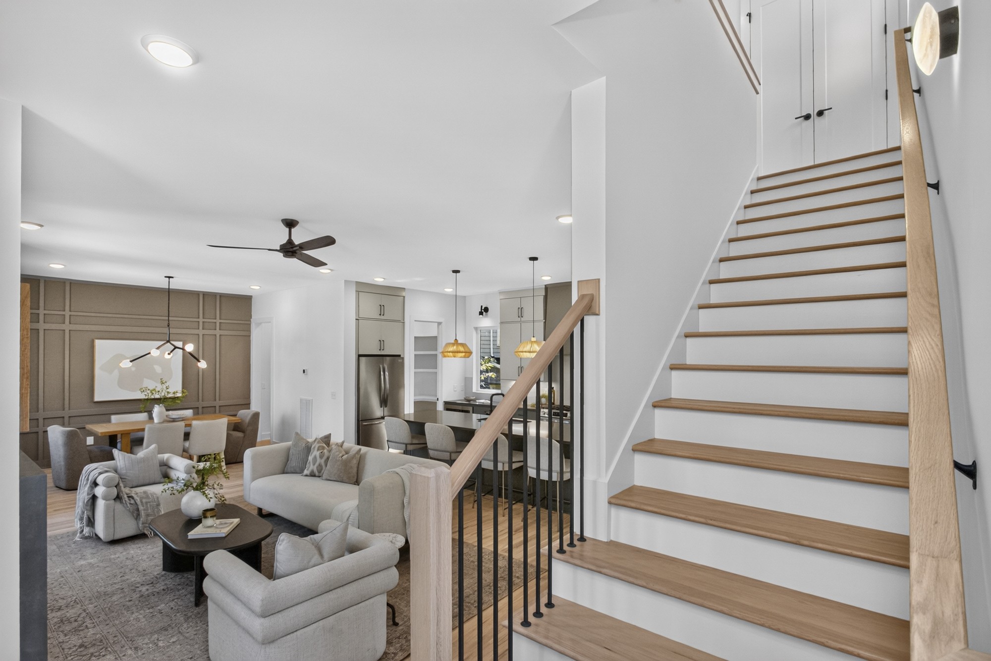 Open-plan living and dining area with a modern kitchen and a wood-tread staircase.
