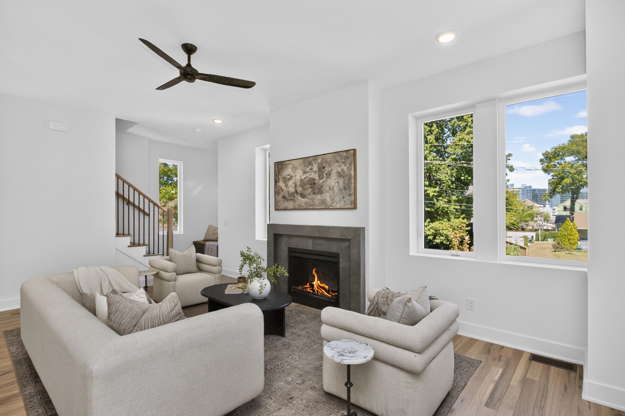 Bright living room with a fireplace, neutral seating, and large windows overlooking the city.