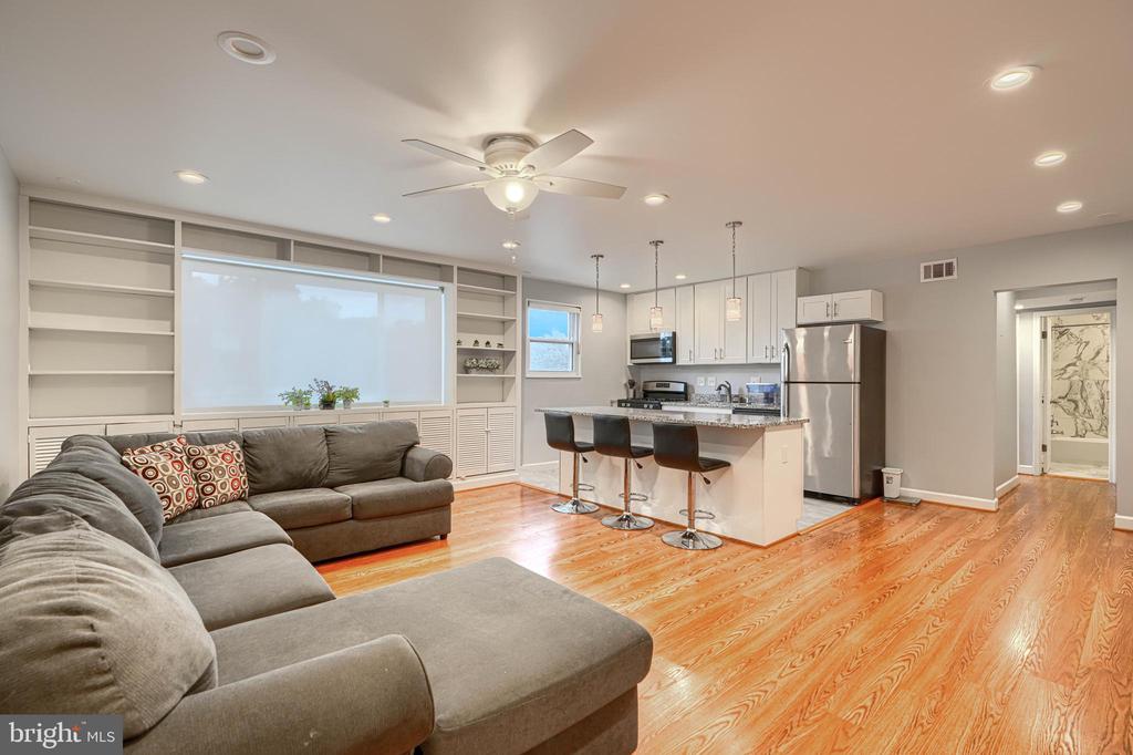 Living room with a large sectional, built-in shelving, and an open kitchen with island.