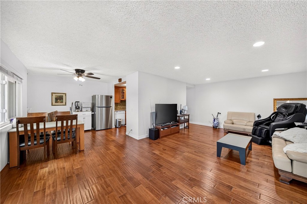 Open-plan living and dining room with glossy wood floors and a ceiling fan.