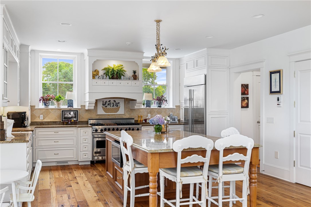 Bright white kitchen with a large range, central wood island, and hardwood floors.