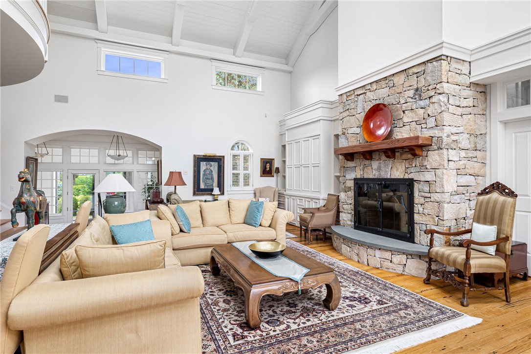 Living room with a stone fireplace, vaulted ceiling, beige sofas, and hardwood floors.