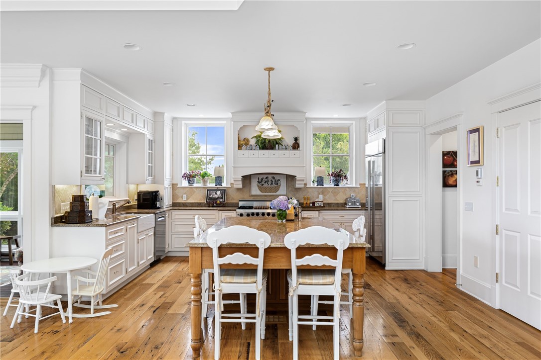 Bright kitchen with a large wood-base island, white cabinetry, and warm hardwood floors.