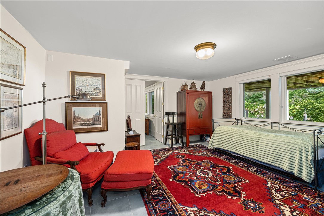 Bedroom with a metal-frame bed, red chairs, and a large patterned red rug.