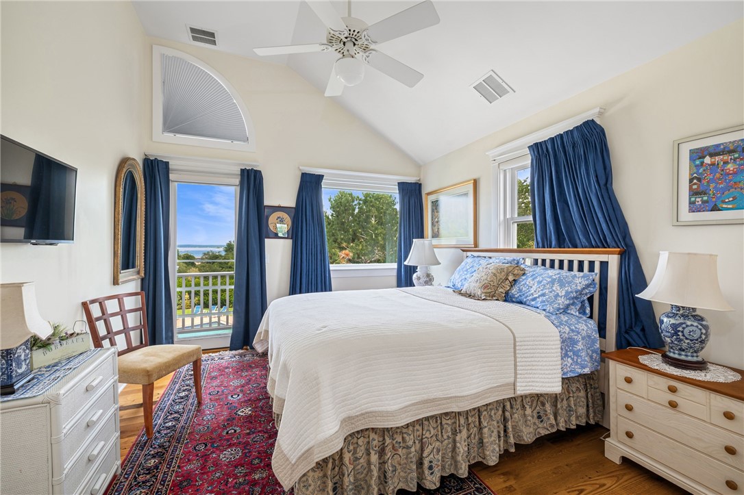 Bedroom with a vaulted ceiling, blue curtains, and ocean views through balcony doors.