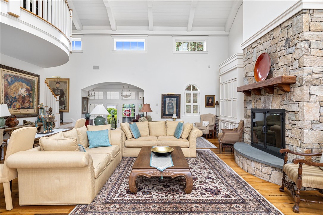 Living room with cream sectional seating, vaulted white ceiling, and a large stone fireplace.