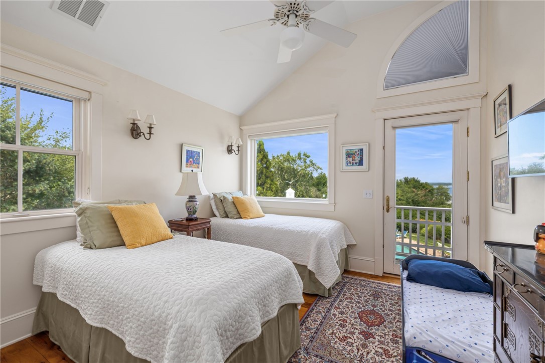 Bedroom with two white-quilted beds, a patterned rug, and a balcony overlooking distant water.