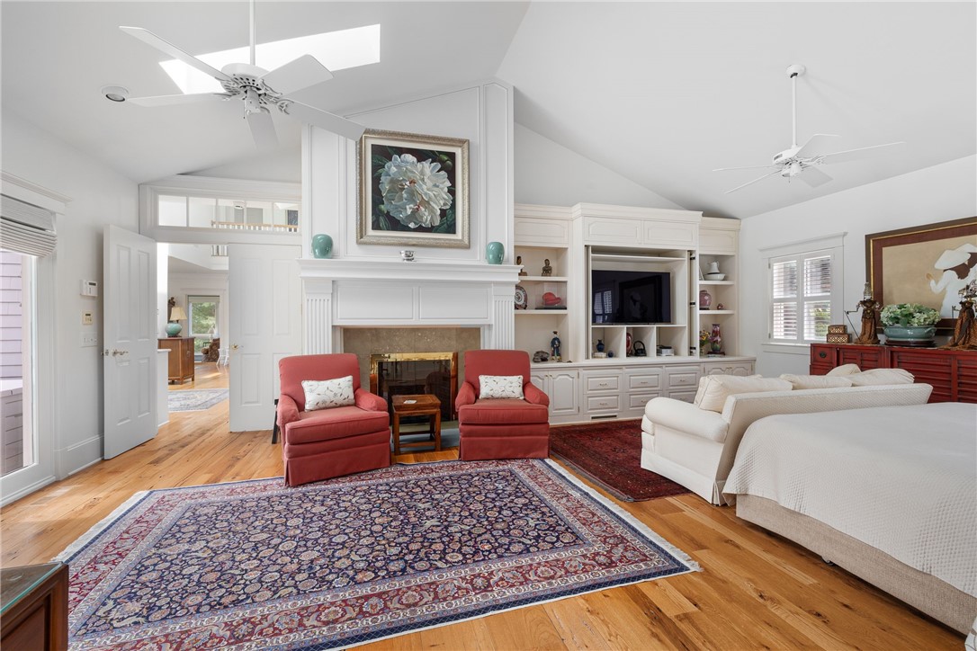 Living room with a white fireplace, built-in cabinetry, red armchairs, and a large patterned rug.