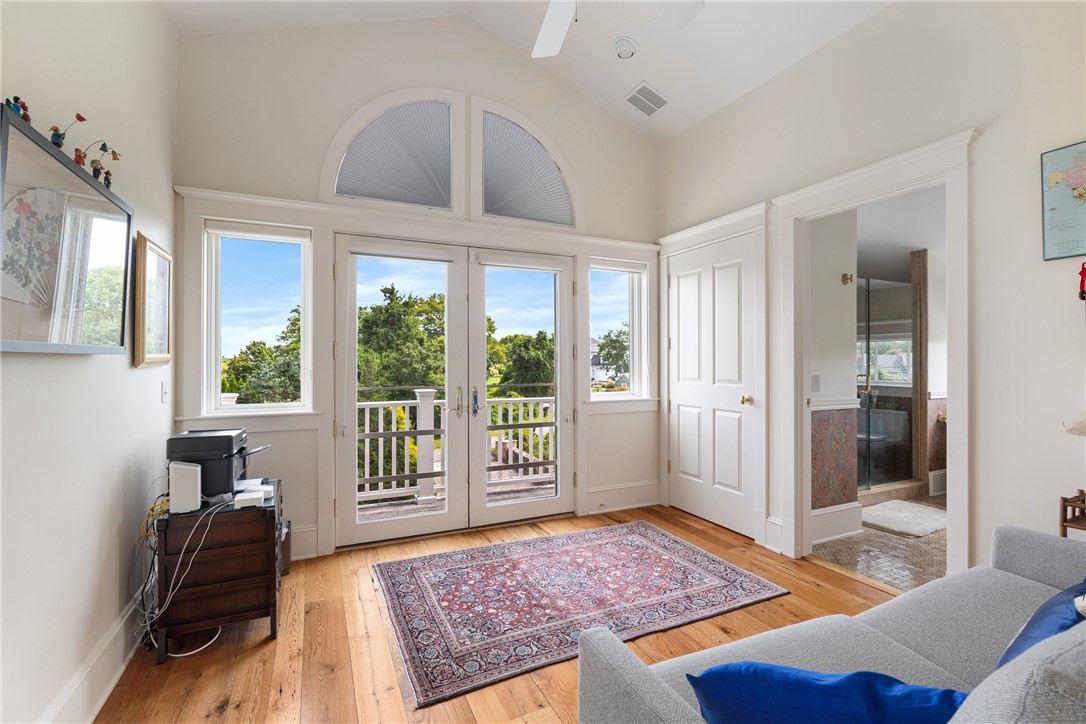 Living room with hardwood floors, a patterned rug, and French doors opening onto a porch.