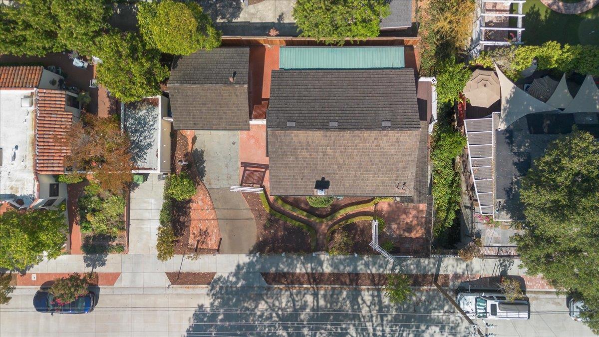 Aerial view of a house with a shingled roof, landscaped front yard, and street frontage.