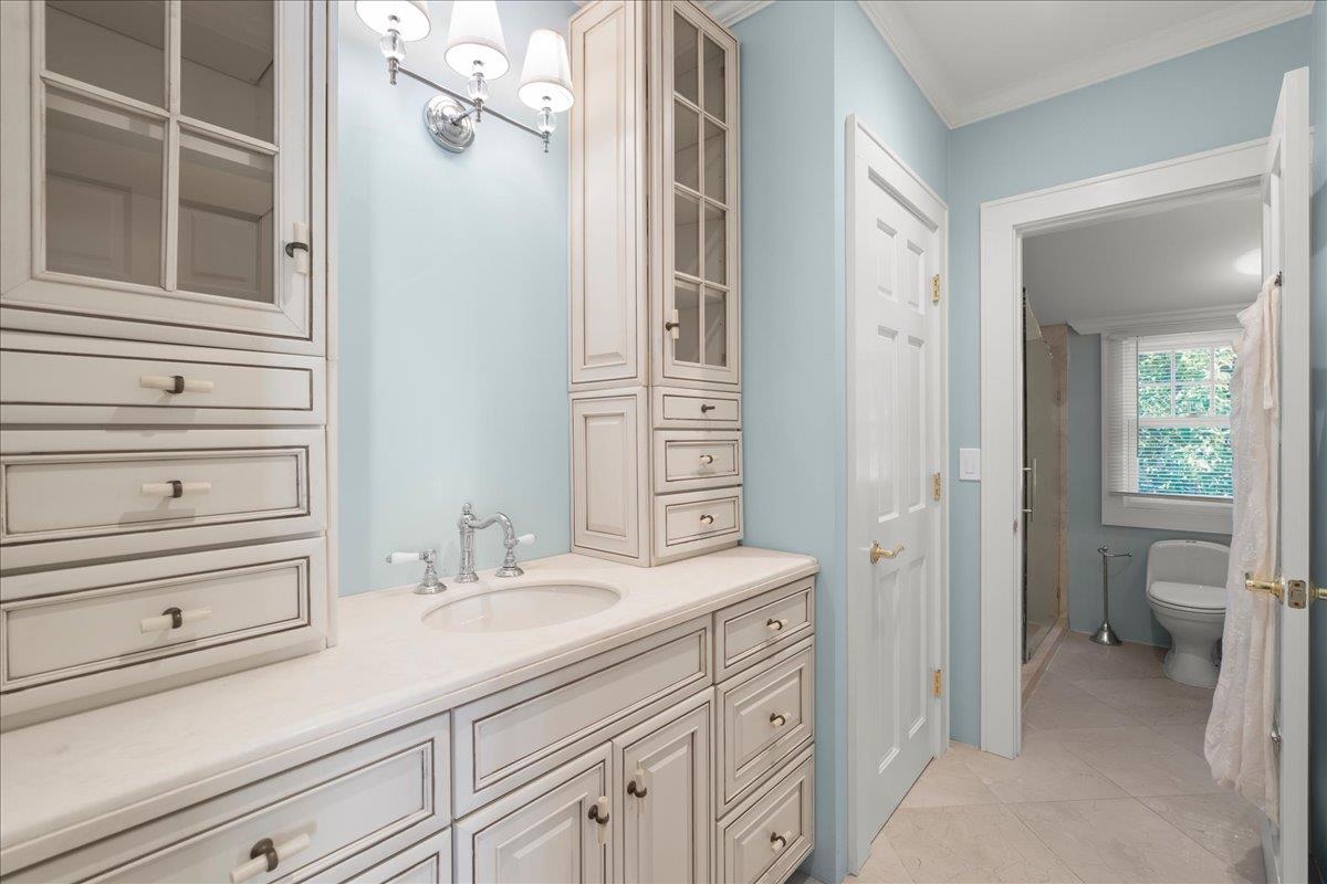 Bathroom with a long white vanity and a doorway to a separate toilet and shower area.