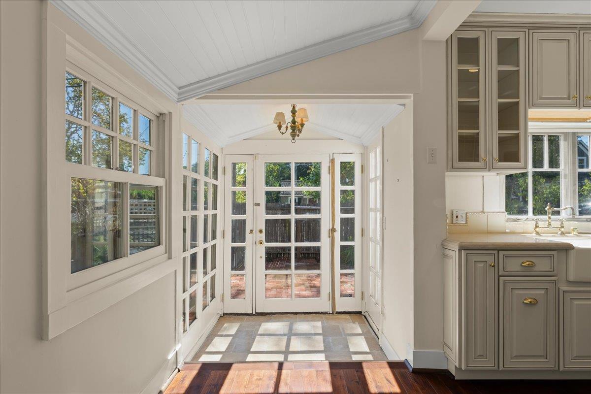Sunroom with a vaulted ceiling, abundant white-framed windows, and glass doors opening to a brick patio.