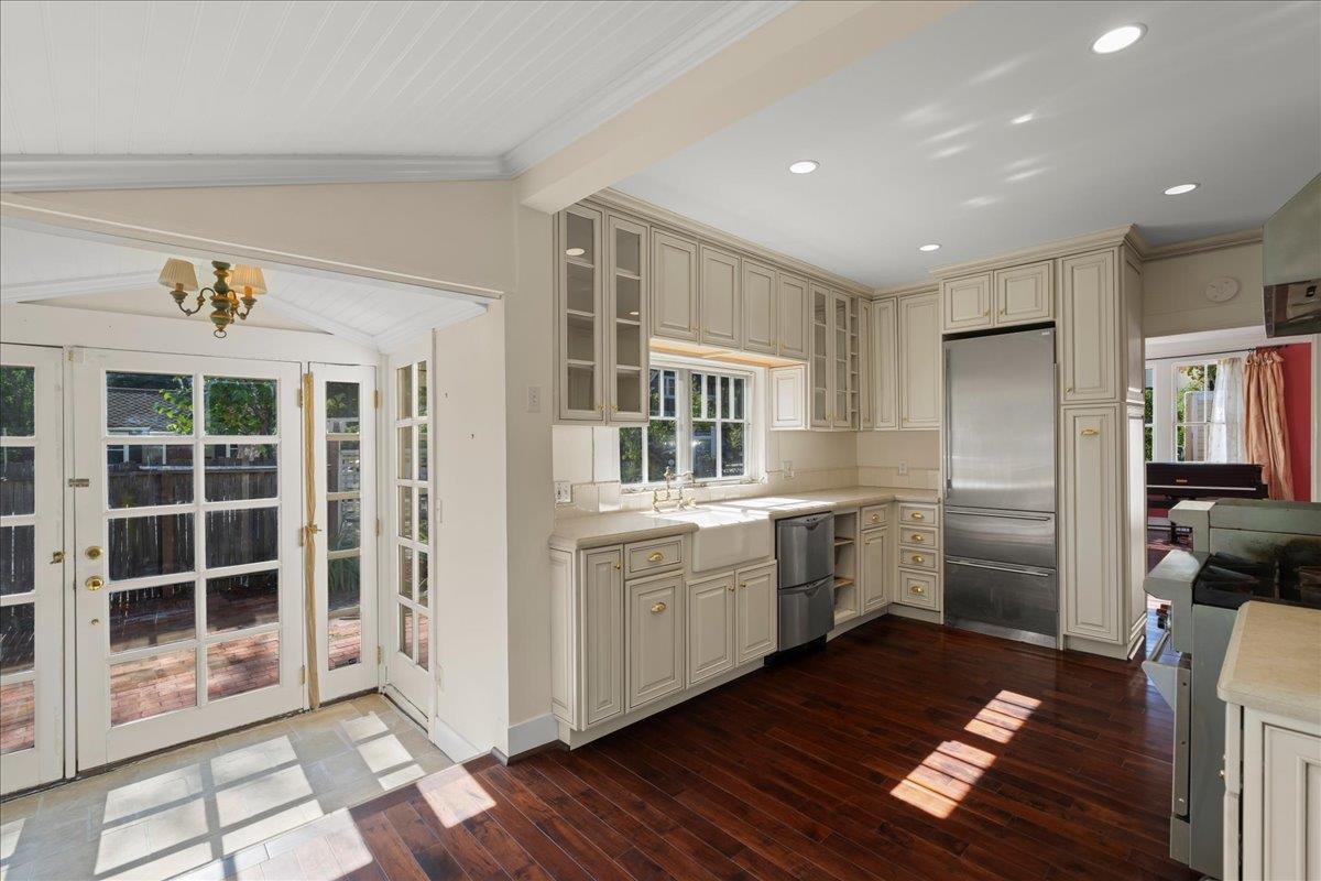 Kitchen with cream cabinets, stainless steel refrigerator, and sunlit French doors opening to a patio.