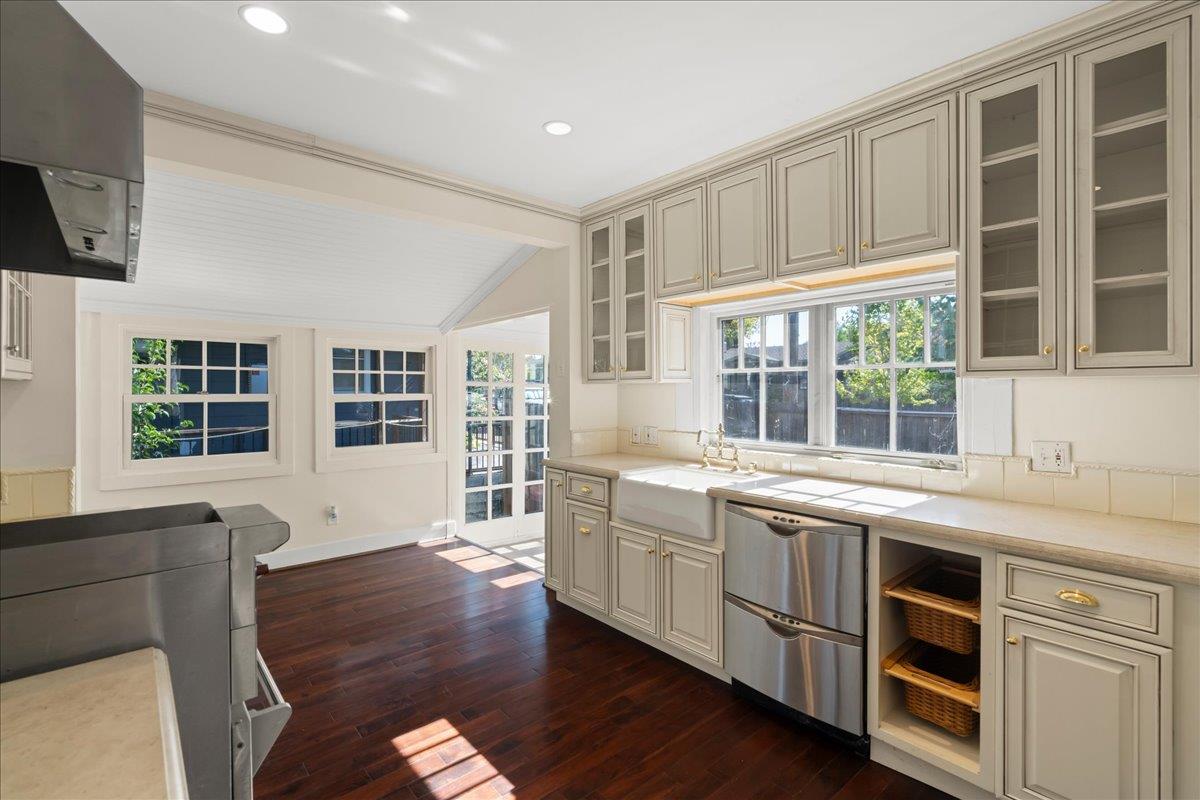 Kitchen with cream cabinets, farmhouse sink, stainless steel dishwashers, and dark hardwood floors.