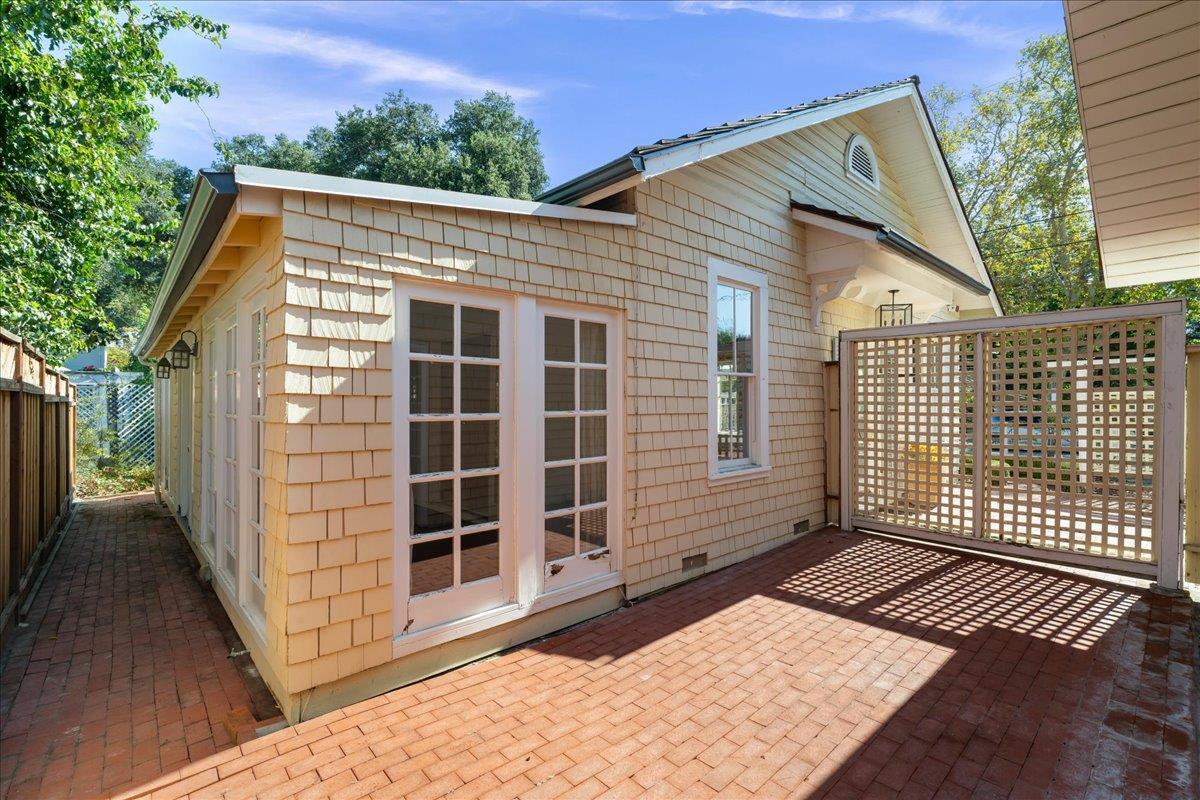 Home’s rear exterior with French doors, a brick patio, and a lattice privacy screen.