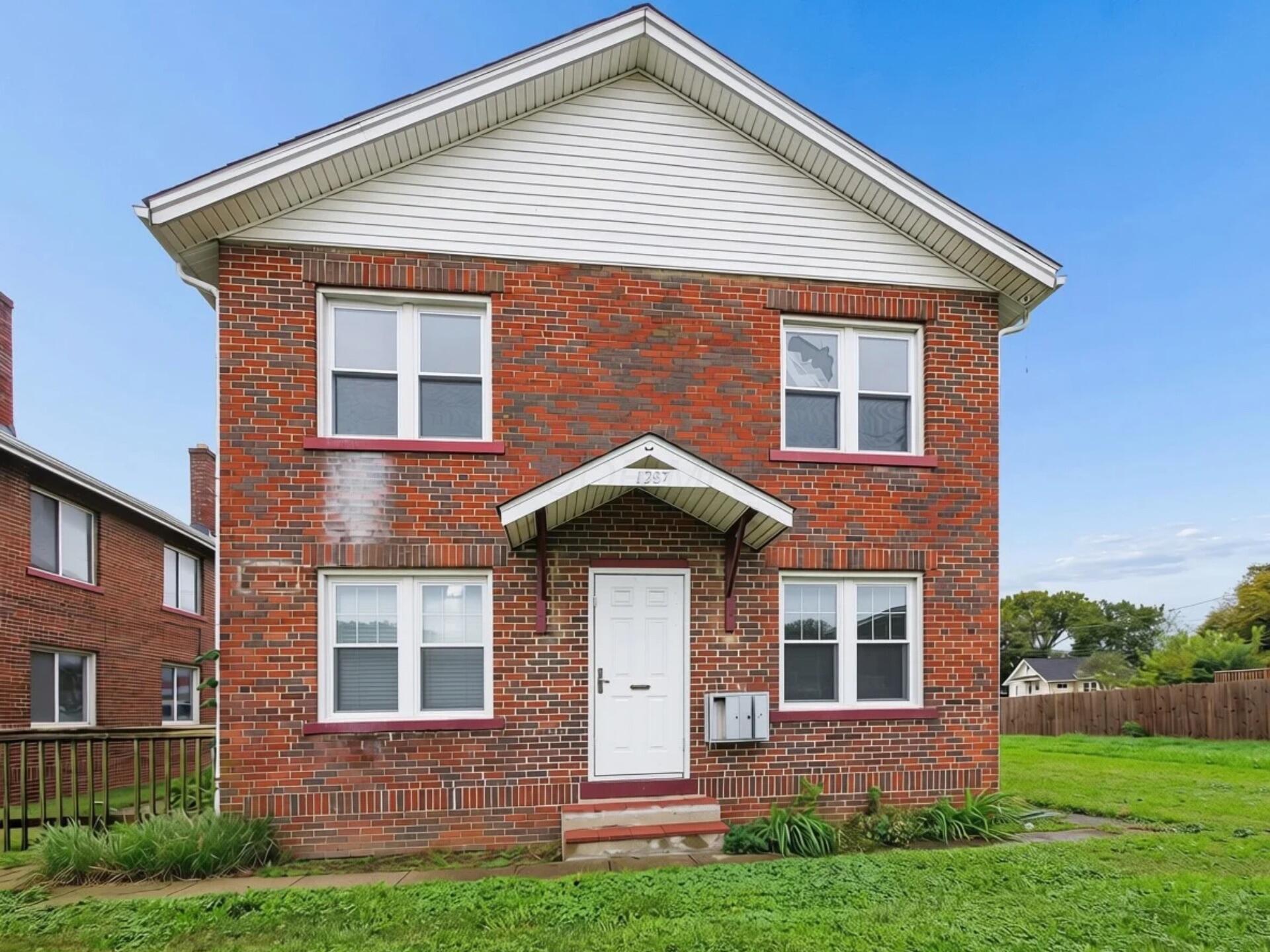 Two-story red brick house with a white gable and covered front entrance.