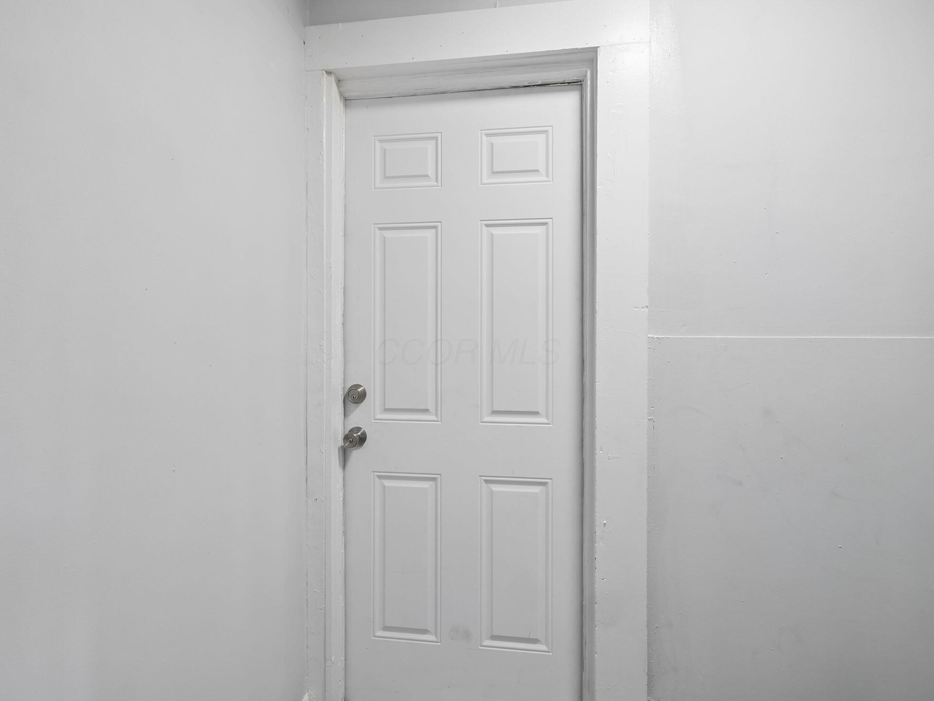 White six-panel interior door with a deadbolt and round doorknob.