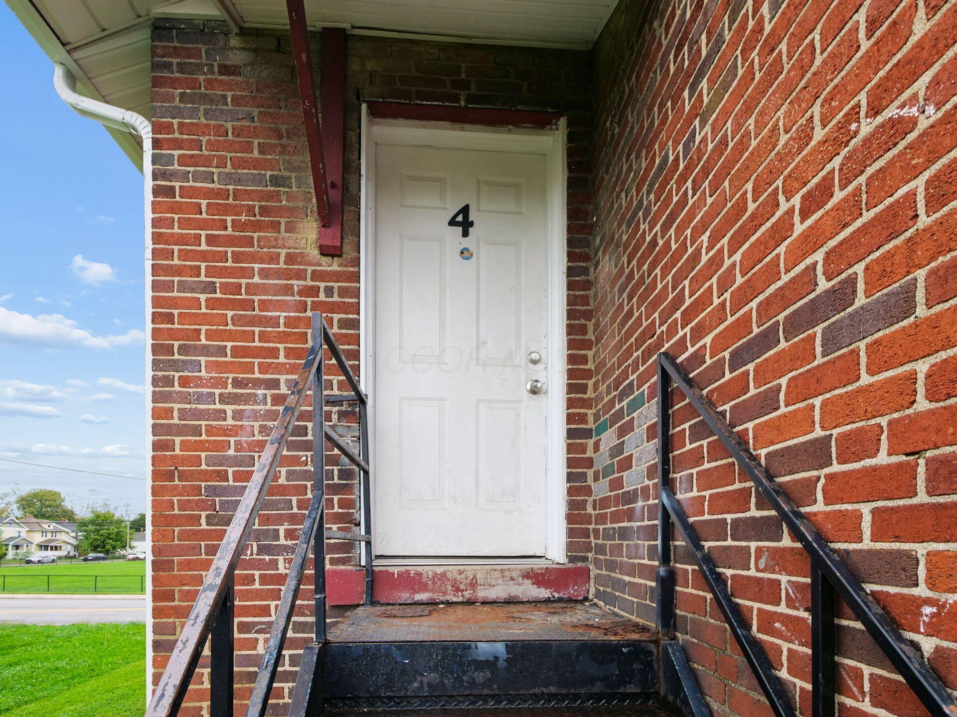 Brick building entrance with a white door marked 4 and worn metal steps.