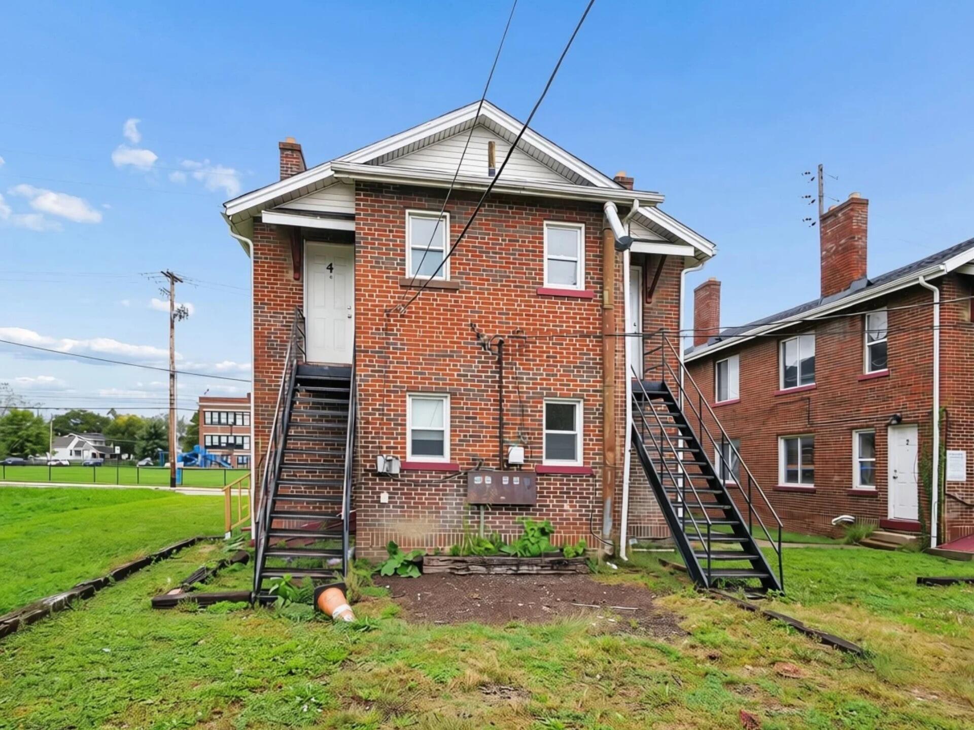 Red-brick multi-unit building with white gable and two exterior staircases.