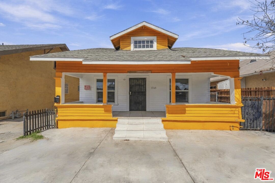 House with a bright yellow-orange porch, central dormer, and concrete driveway.