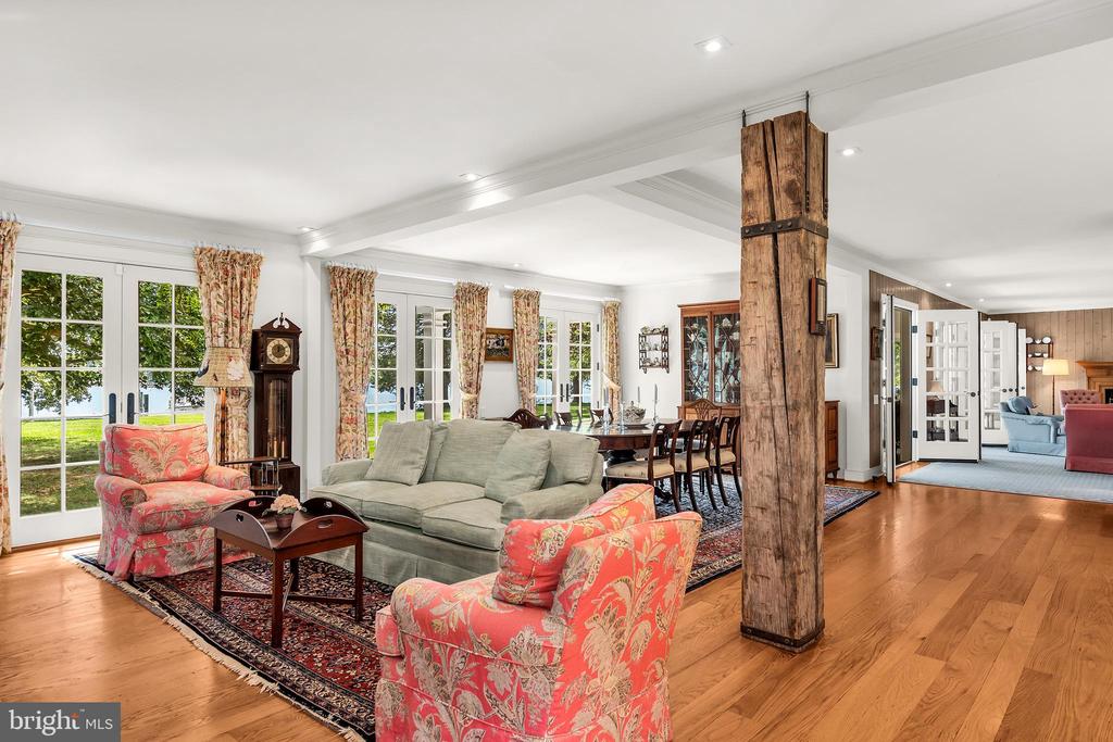 Living room with floral armchairs, French doors, hardwood floors, and a rustic timber support post.