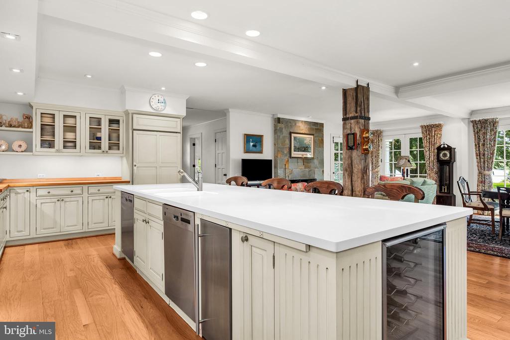 Open kitchen with a large white island, stainless-steel appliances, and adjoining living and dining areas.