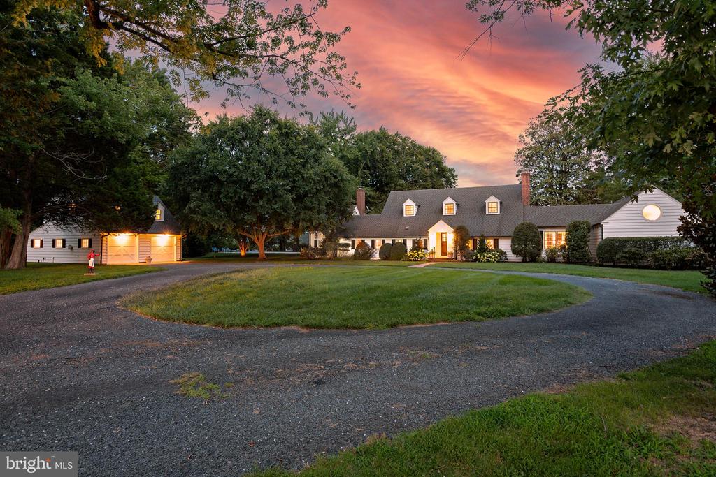 White house and attached garage with a circular driveway under a pink dusk sky.