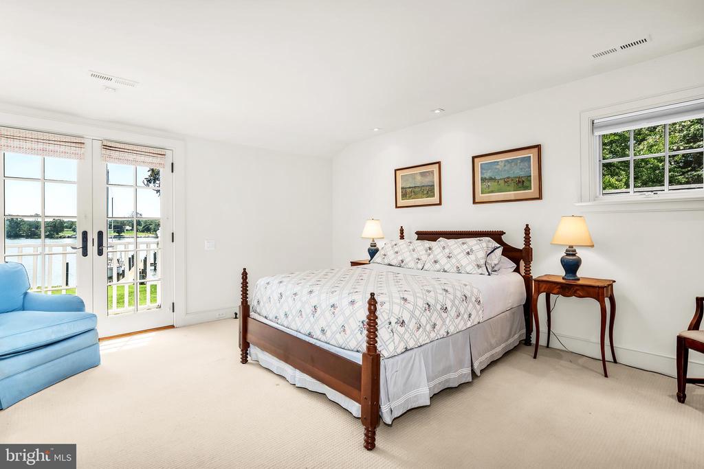 Bedroom with a four-poster bed and French doors overlooking the water.