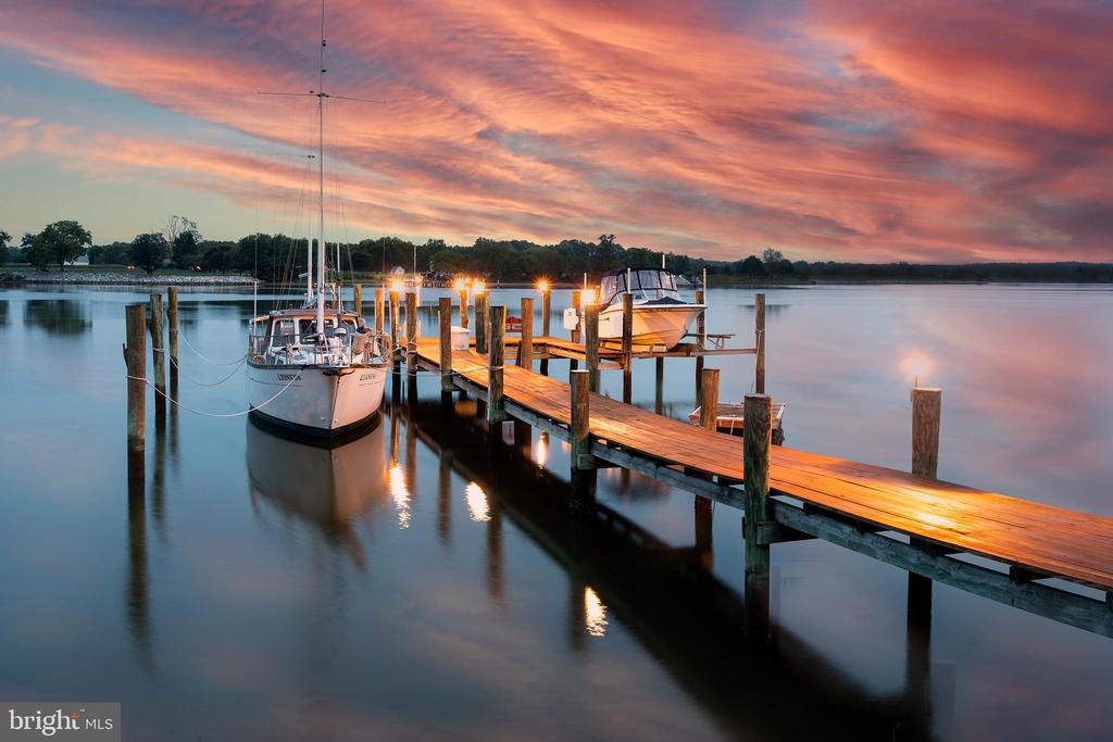 Waterfront dock with two moored boats beneath a vivid pink sunset.
